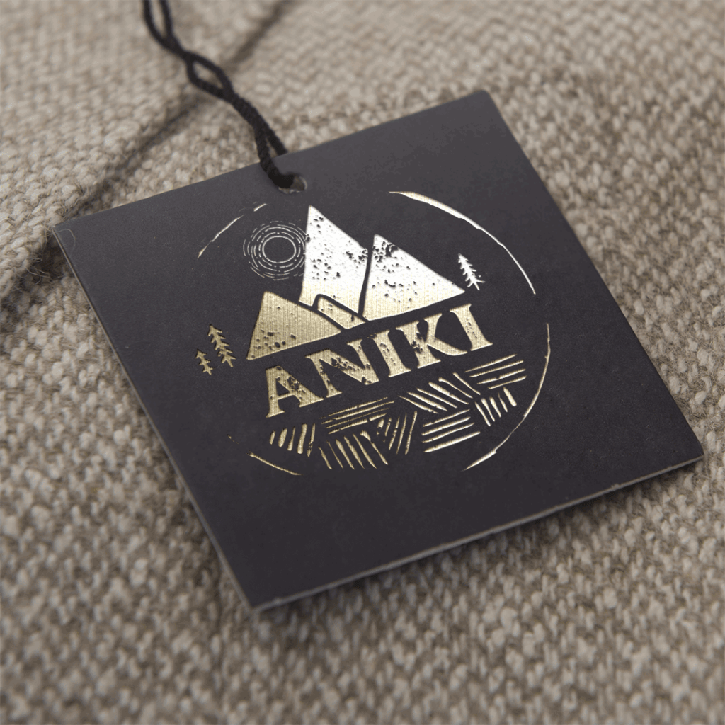 Aniki brand logo in gold foil on a black swing tag