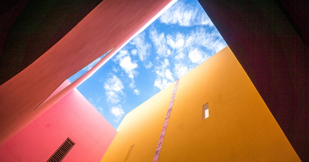 Looking upwards to a blue sky surrounded by buildings for #designtips article Why does my business need a Sales Funnel?