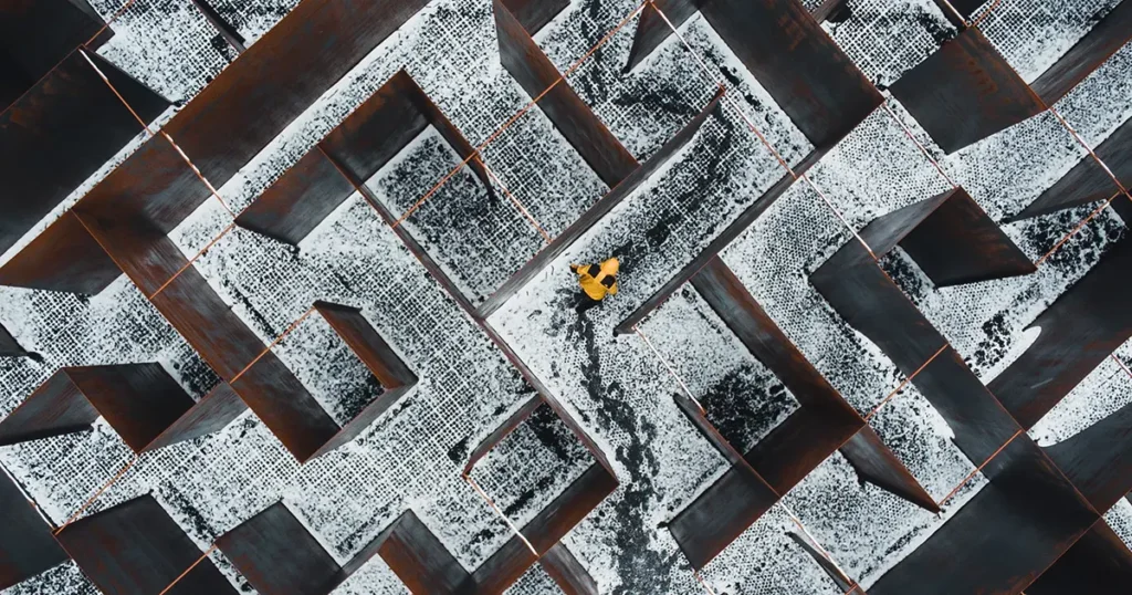 Birds eye view of a person in a yellow jacket trying to find there way out of a snowy maze for #designtips article Collating Website Content