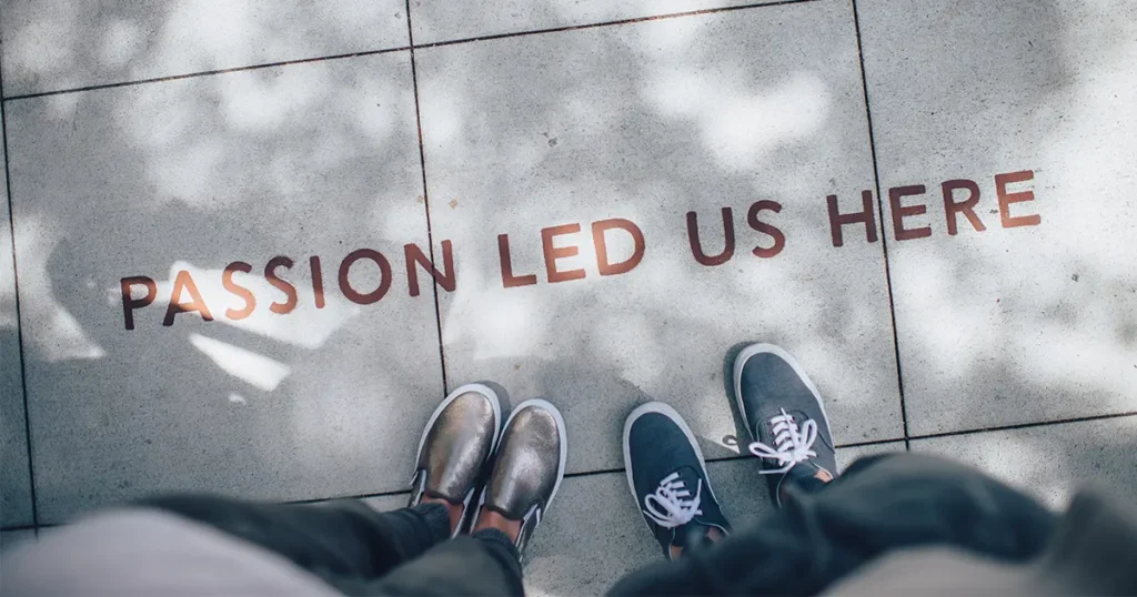 Camera looking down at two sets of feet next to test sating ‘passion led us here’ for #designtips article The Power of Brand Consistancy