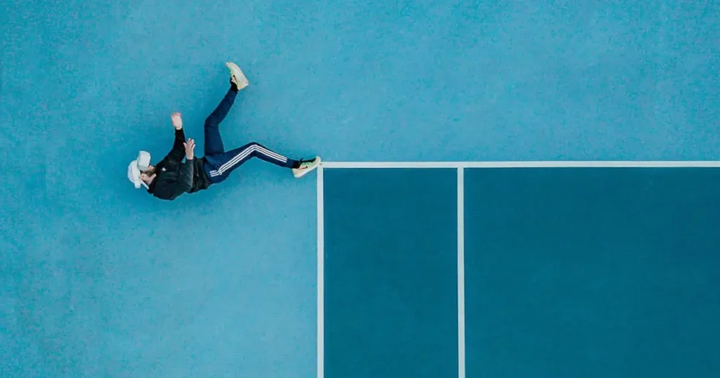 Surreal photo of man walking along the edge of a tennis court for blog article how big is your office digital footprint