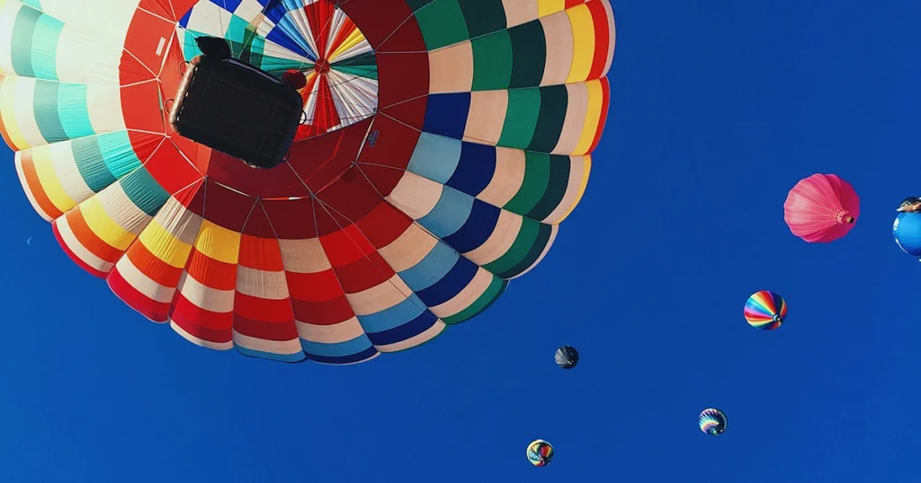 Looking upwards into a deep blue summer sky at a group pf hot air balloons for #designtips article How to Write a Good Business Plan