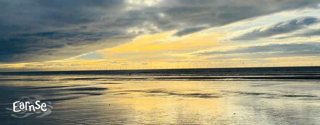 Photograph of Earnse Bay at sunset with wide sandy beach, ocean waves and stormy sky