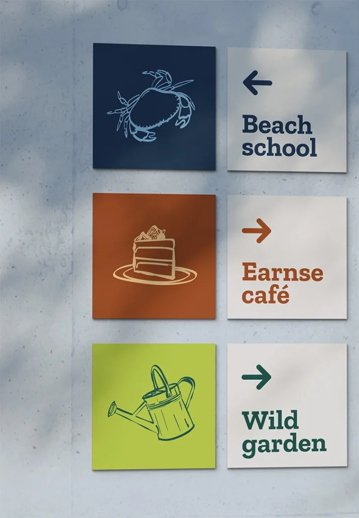 Directional signs at Earnse featuring two squares — an icon on one side and the area with an arrow on the other — pointing to the Beach School, Earnse Café, and Wild Garden as part of the Earnse brand design